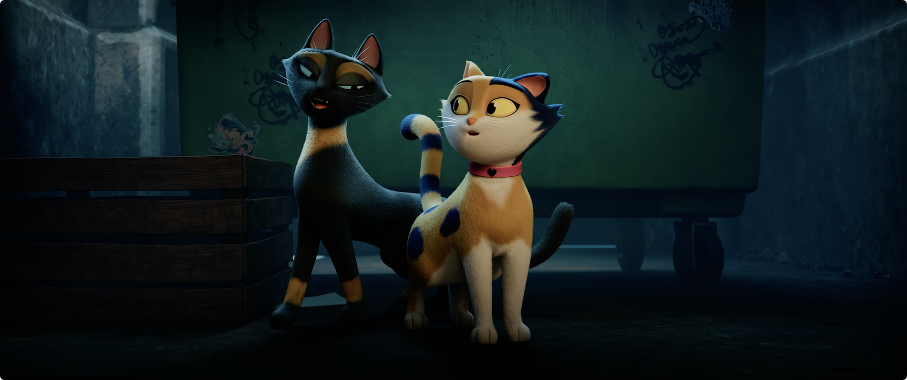 Twee schattige katten staan naast elkaar in een verlicht steegje, met een vuilnisbak op de achtergrond.