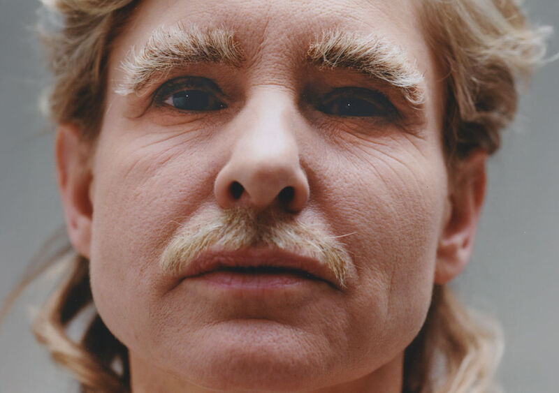 Een close-up portret van een persoon met een lichte baard en opvallende wenkbrauwen, met een neutrale gezichtsuitdrukking.