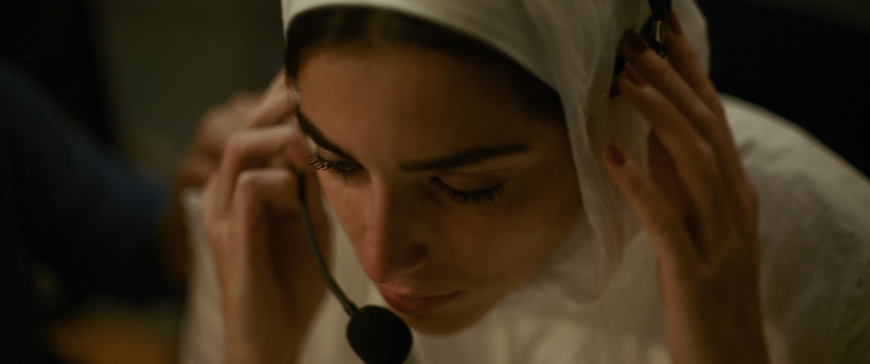 Een vrouw met een hoofddoek en een headset, gefocust terwijl ze in een bedrijfomgeving werkt.