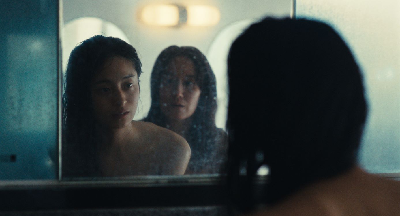 Twee vrouwen kijken in een spiegel, een van hen is zichtbaar in de reflectie, met een dromerige uitstraling.